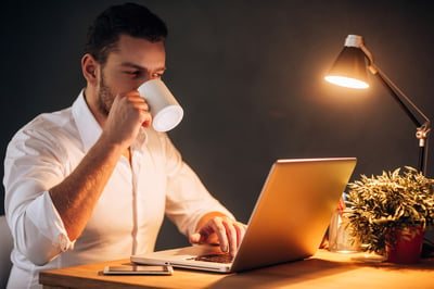 Man drinking coffee at night while working