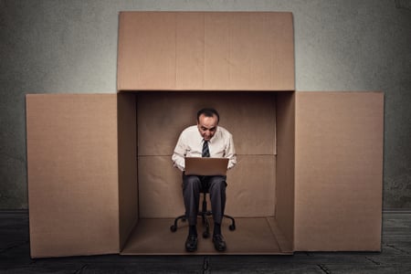 Man on laptop inside cardboard box