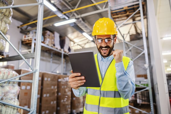 Happy man in warehouse looking at tablet